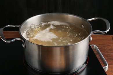 Photo of Fresh tagliatelle pasta boiling in pot with water on electric stove, closeup