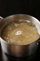 Photo of Fresh tagliatelle pasta boiling in pot with water on electric stove, closeup