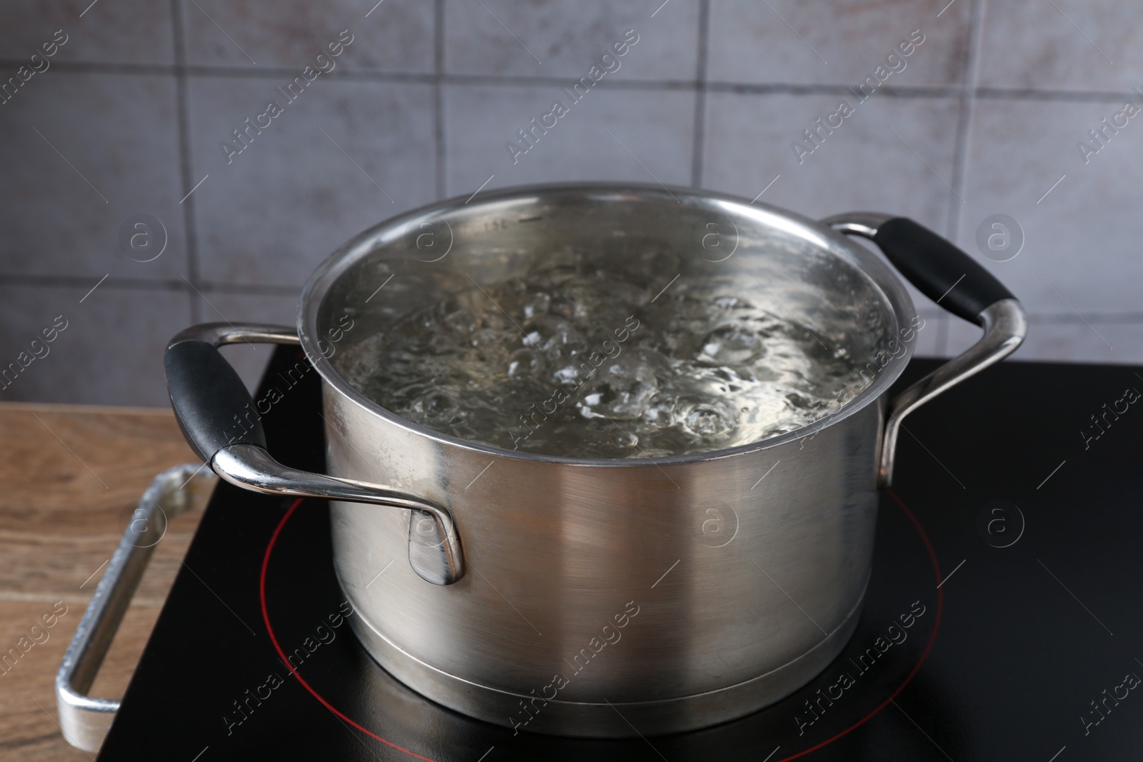 Metal pot with boiling water on stove in kitchen, closeup Photo of Metal pot with boiling water on stove in kitchen, closeup
