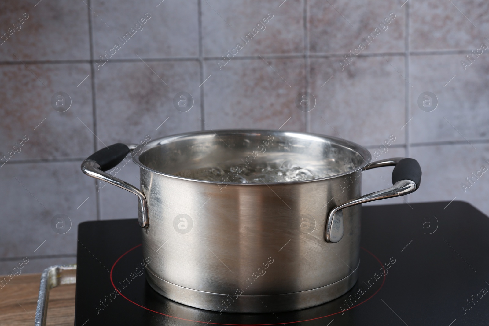 Metal pot with boiling water on stove in kitchen, closeup Photo of Metal pot with boiling water on stove in kitchen, closeup