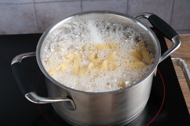 Photo of Fresh pasta boiling in pot with water on electric stove, closeup