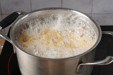 Photo of Fresh pasta boiling in pot with water on electric stove, closeup