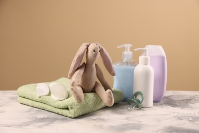 Photo of Baby accessories and bathing products on grey textured table against beige background