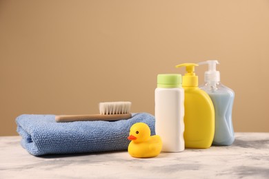 Photo of Baby accessories and bathing products on grey textured table against beige background