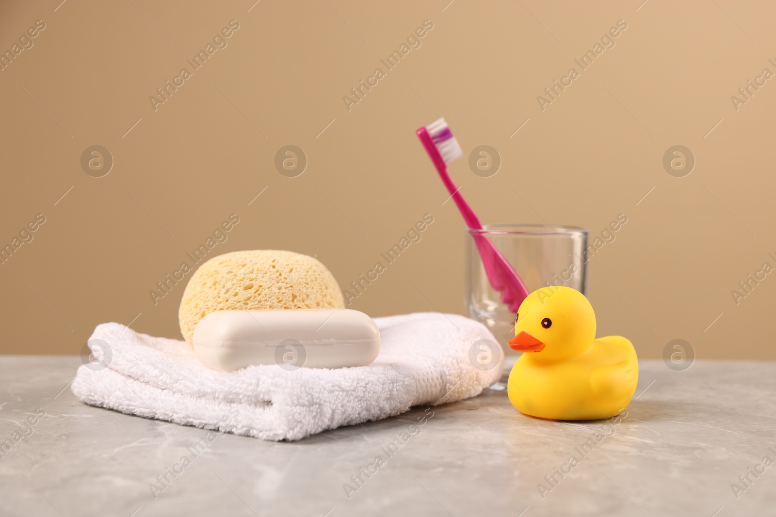 Photo of Baby accessories and bathing products on grey textured table against beige background
