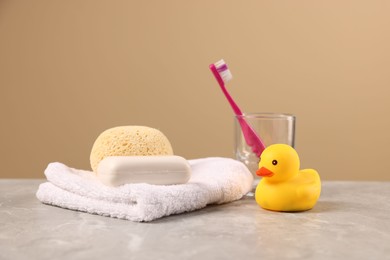 Photo of Baby accessories and bathing products on grey textured table against beige background