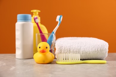 Photo of Baby accessories and bathing products on grey table against orange background, closeup