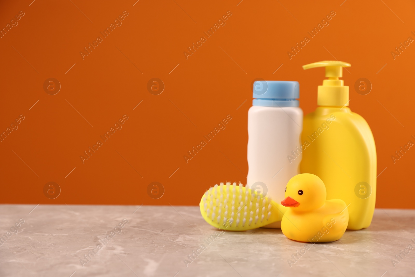 Photo of Baby accessories and bathing products on grey table against orange background, space for text