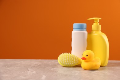 Photo of Baby accessories and bathing products on grey table against orange background, space for text