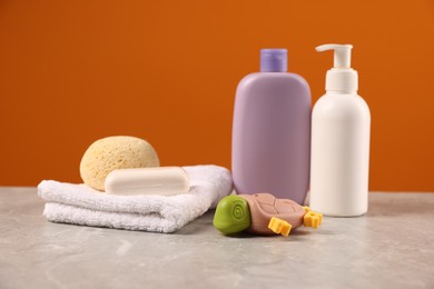 Photo of Baby accessories and bathing products on grey table against orange background