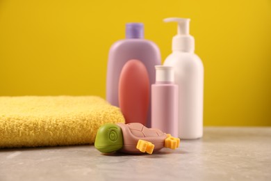 Photo of Baby accessories and bathing products on grey table against yellow background, closeup