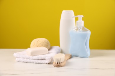 Photo of Baby accessories and bathing products on white marble table against yellow background