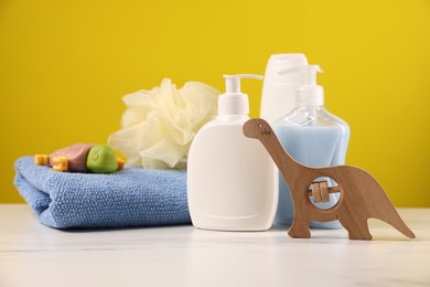 Photo of Baby accessories and bathing products on white marble table against yellow background