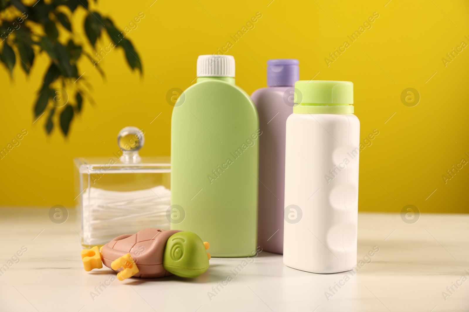 Photo of Baby accessories and bathing products on white marble table against yellow background