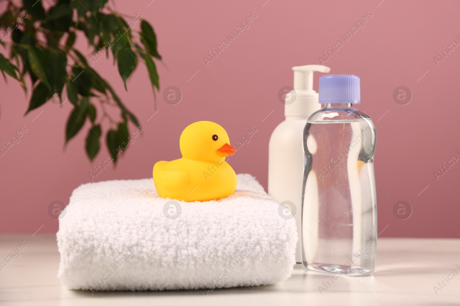 Photo of Baby accessories and bathing products on white marble table against pink background