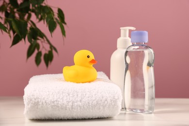 Photo of Baby accessories and bathing products on white marble table against pink background