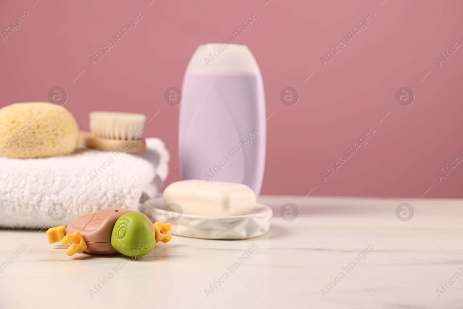 Photo of Baby accessories and bathing products on white marble table against pink background, closeup. Space for text