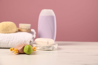 Photo of Baby accessories and bathing products on white marble table against pink background, closeup. Space for text