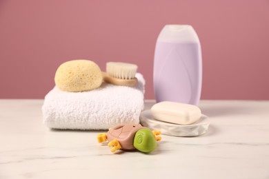 Photo of Baby accessories and bathing products on white marble table against pink background, closeup