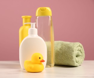 Photo of Baby accessories and bathing products on white marble table against pink background
