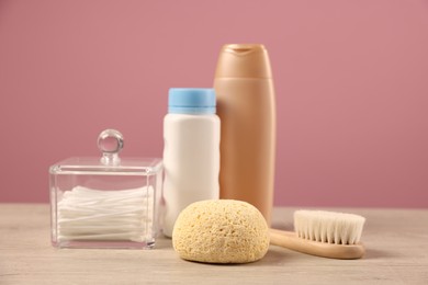 Photo of Baby accessories and bathing products on wooden table against pink background
