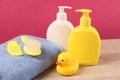 Photo of Baby accessories and bathing products on wooden table against pink background, closeup