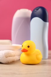 Photo of Baby accessories and bathing products on wooden table against pink background, closeup