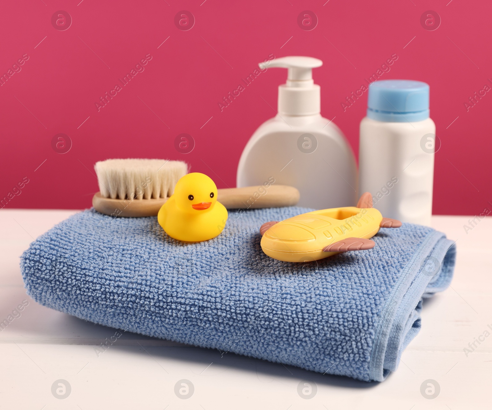 Photo of Baby accessories and bathing products on white wooden table against pink background