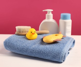 Photo of Baby accessories and bathing products on white wooden table against pink background
