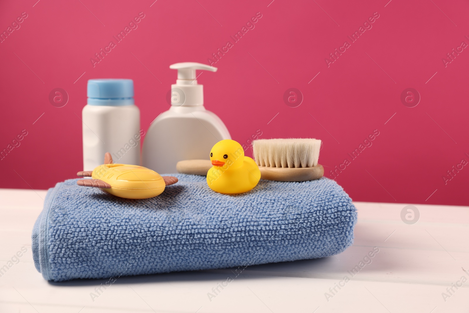 Photo of Baby accessories and bathing products on white wooden table against pink background