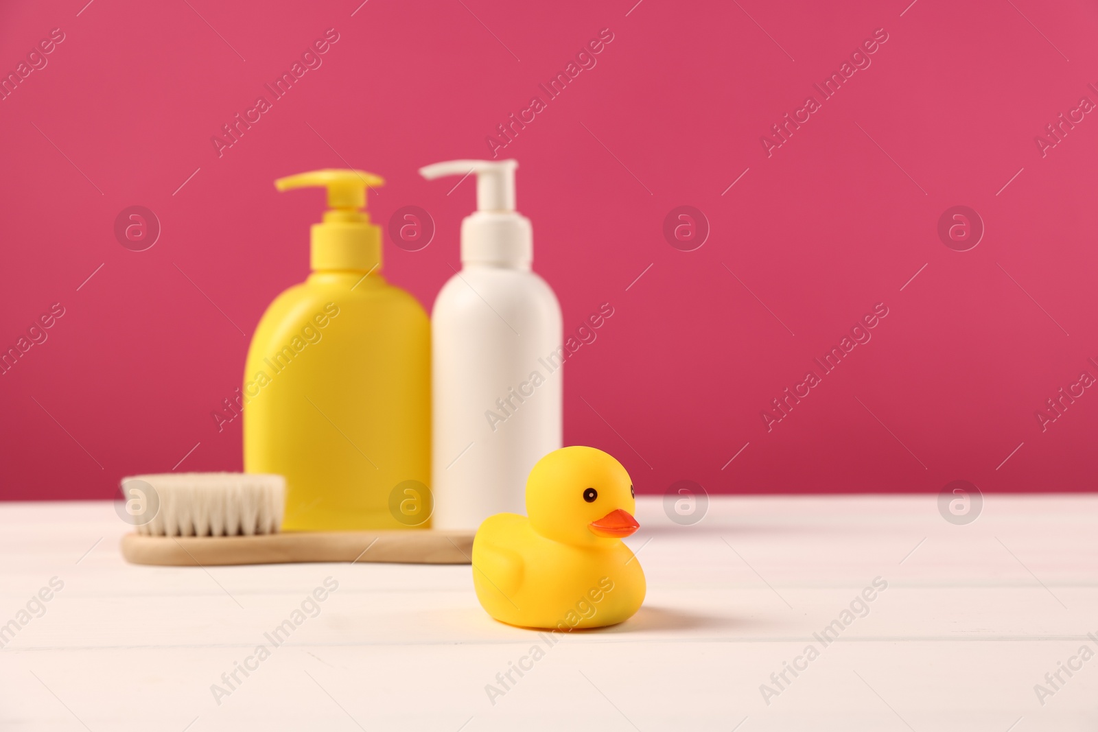 Photo of Baby accessories and bathing products on white wooden table against pink background, space for text