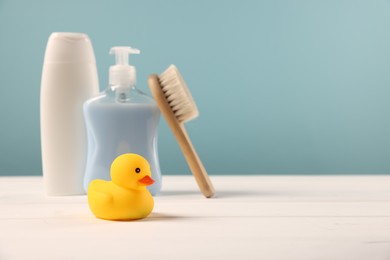 Photo of Baby accessories and bathing products on white wooden table against light blue background, space for text