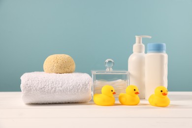 Photo of Baby accessories and bathing products on white wooden table against light blue background