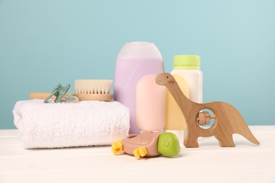 Photo of Baby accessories and bathing products on white wooden table against light blue background