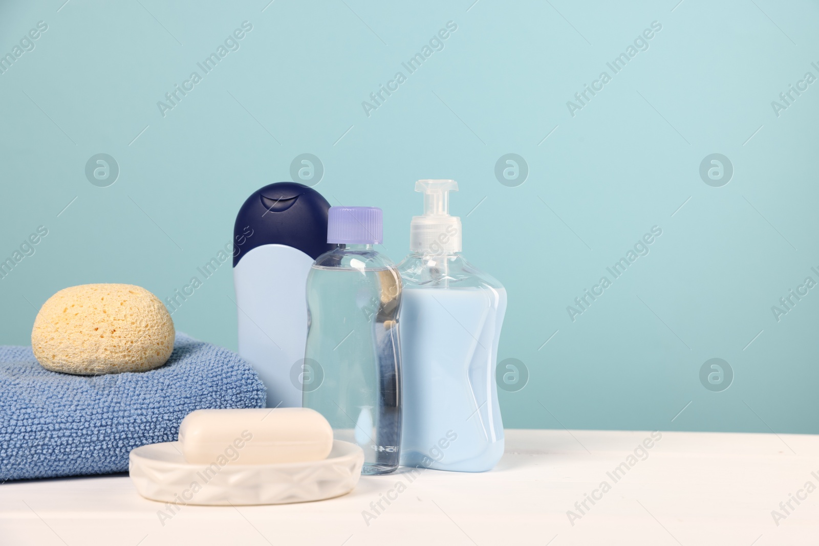Photo of Baby accessories and bathing products on white wooden table against light blue background, space for text