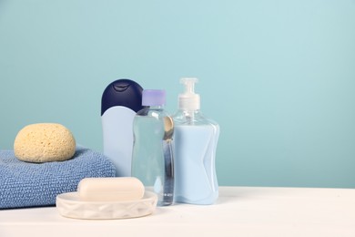 Photo of Baby accessories and bathing products on white wooden table against light blue background, space for text