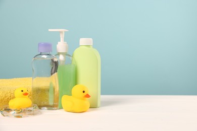 Photo of Baby accessories and bathing products on white wooden table against light blue background, space for text