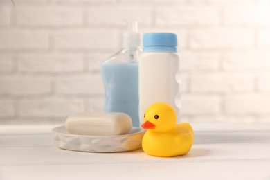 Photo of Baby accessories and bathing products on white wooden table near brick wall, closeup