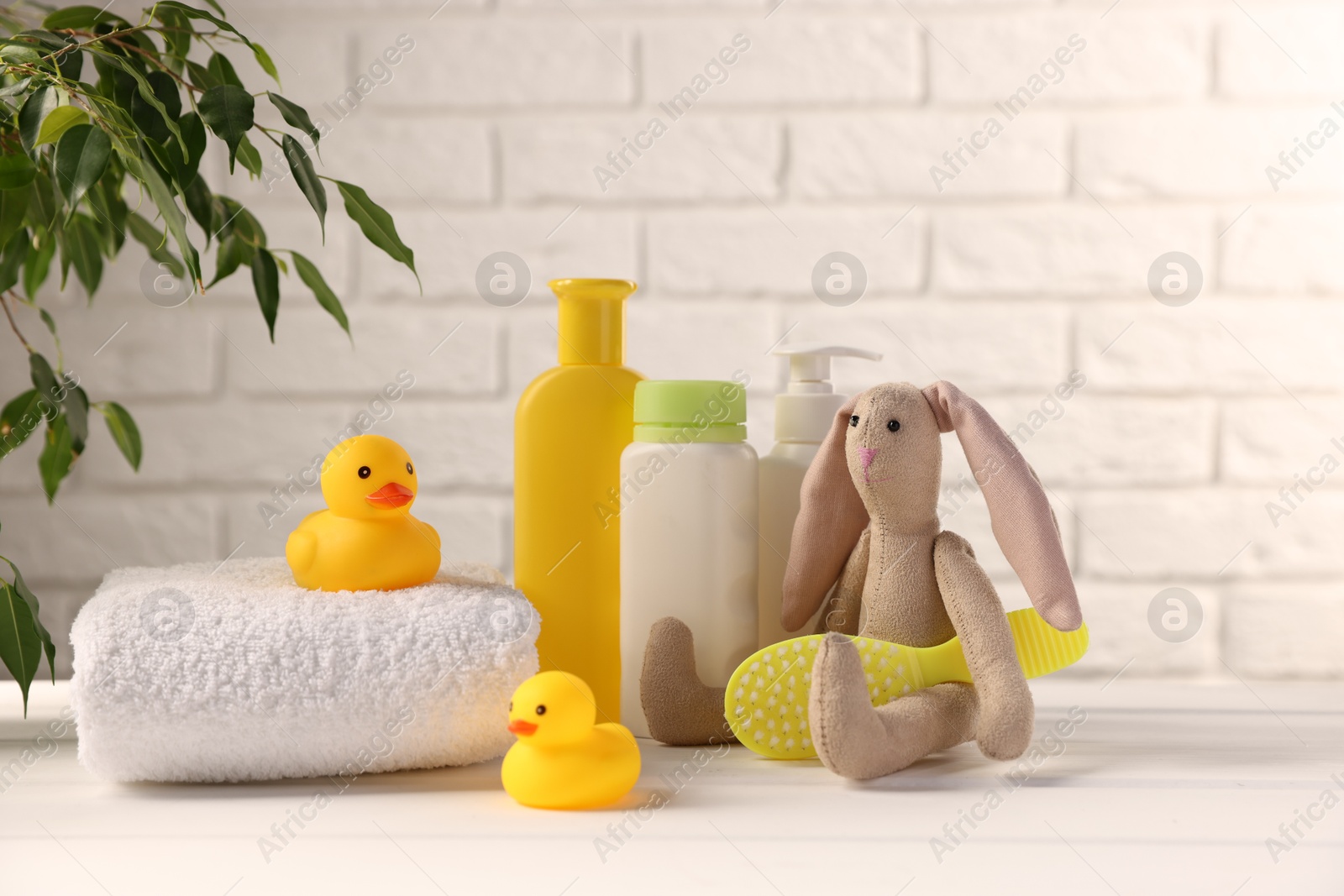 Photo of Baby accessories and bathing products on white wooden table near brick wall