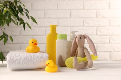 Photo of Baby accessories and bathing products on white wooden table near brick wall