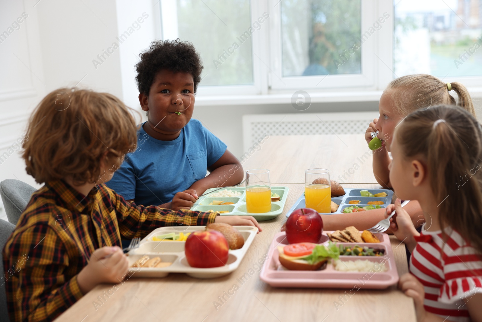 Little kids eating lunch at wooden table in school canteen Photo of Little kids eating lunch at wooden table in school canteen