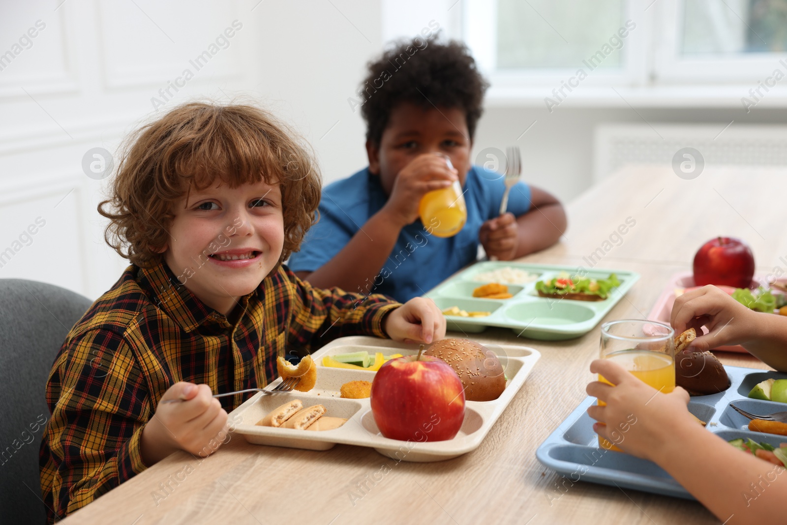 Little kids eating lunch at wooden table in school canteen Photo of Little kids eating lunch at wooden table in school canteen
