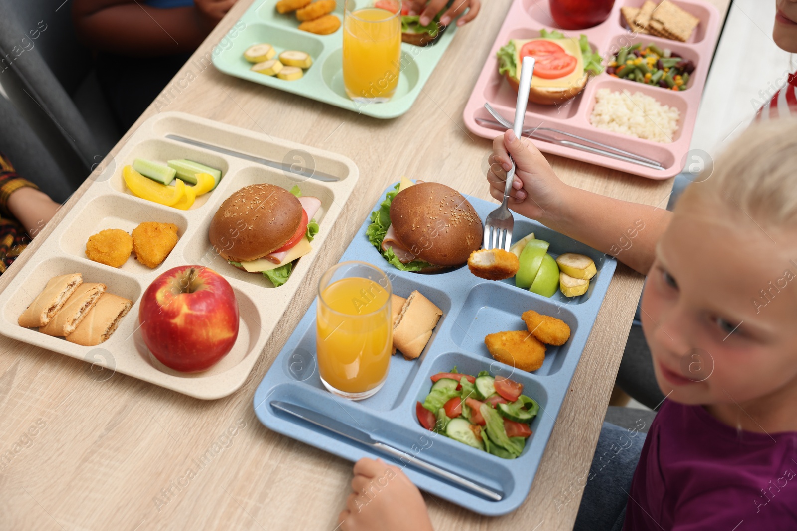 Little kids eating lunch at wooden table in school cafeteria, above view Photo of Little kids eating lunch at wooden table in school cafeteria, above view