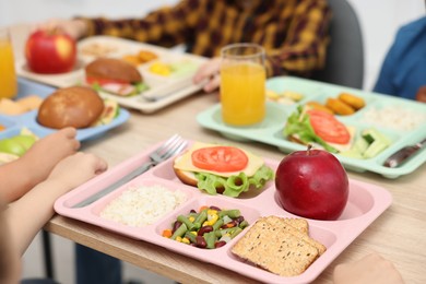 Photo of Little kids eating lunch at wooden table in school canteen, closeup
