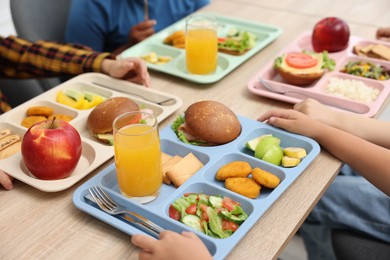 Photo of Little kids eating lunch at wooden table in school canteen, closeup