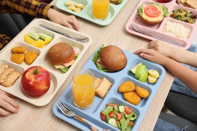Photo of Little kids eating lunch at wooden table in school canteen, closeup