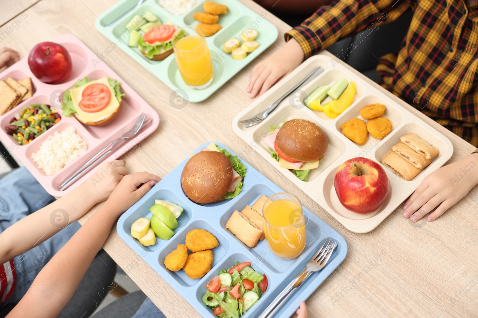 Little kids eating lunch at wooden table in school canteen, closeup Photo of Little kids eating lunch at wooden table in school canteen, closeup