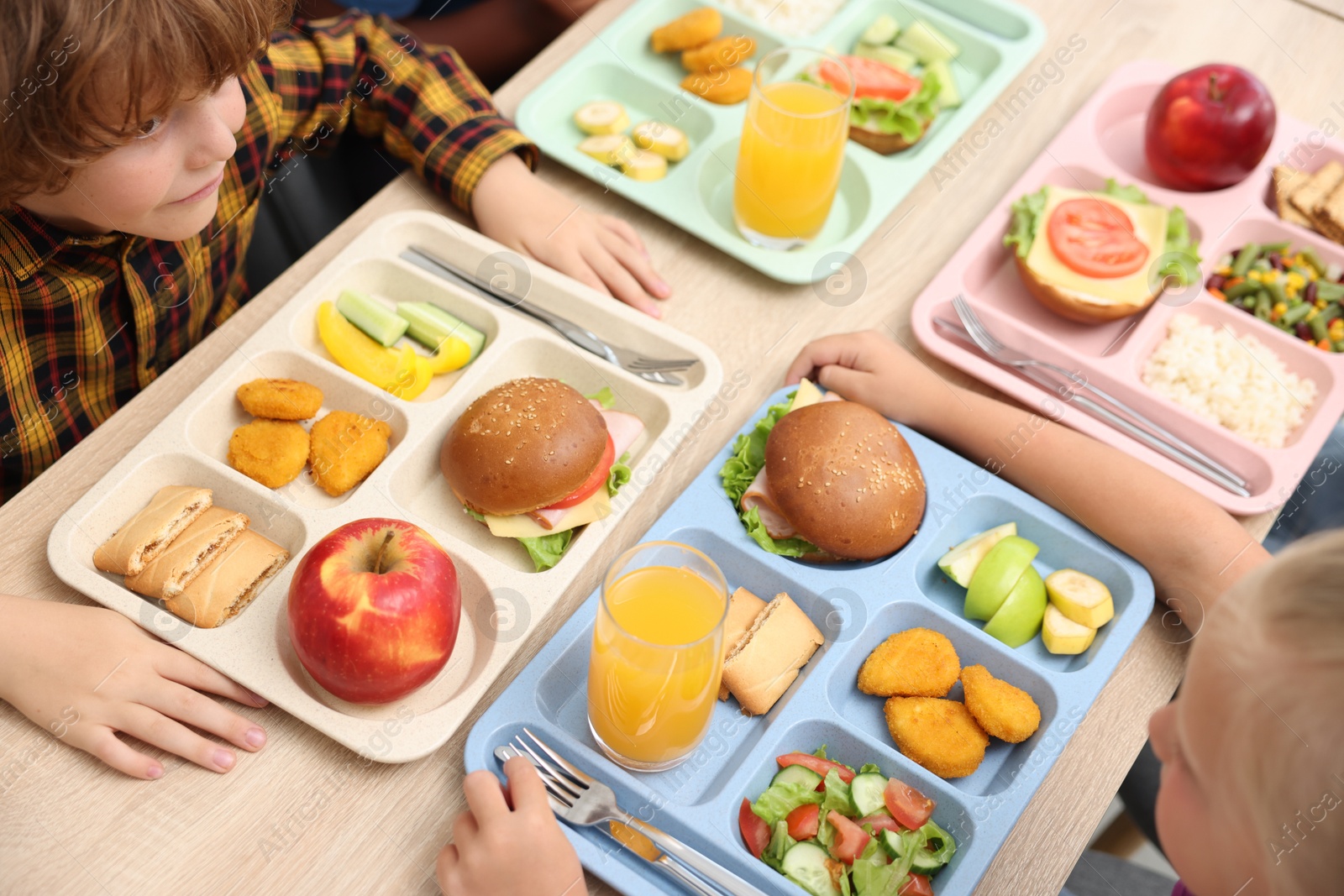 Little kids eating lunch at wooden table in school cafeteria, above view Photo of Little kids eating lunch at wooden table in school cafeteria, above view