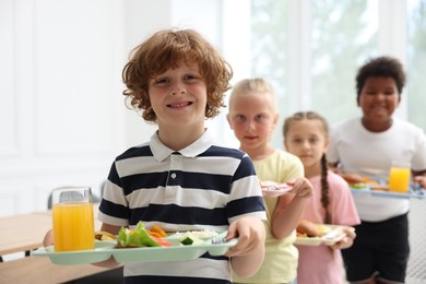 Photo of Little kids with trays of tasty food in school canteen, selective focus