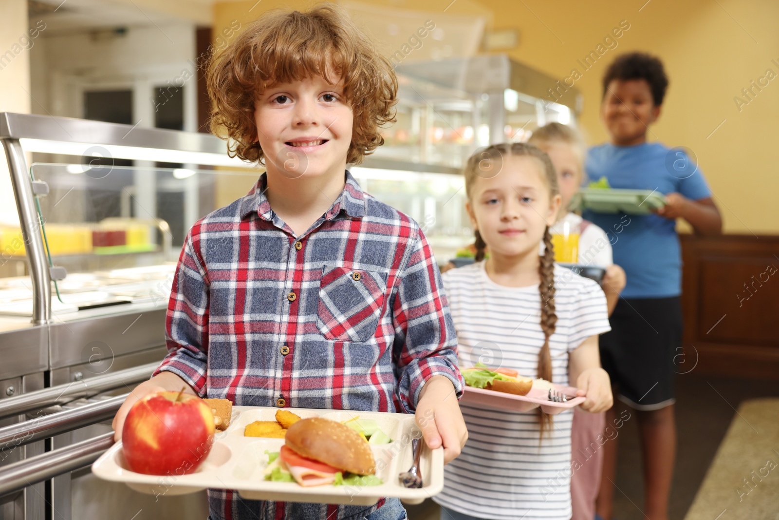 Little boy with tray of tasty food in school canteen, selective focus Photo of Little boy with tray of tasty food in school canteen, selective focus